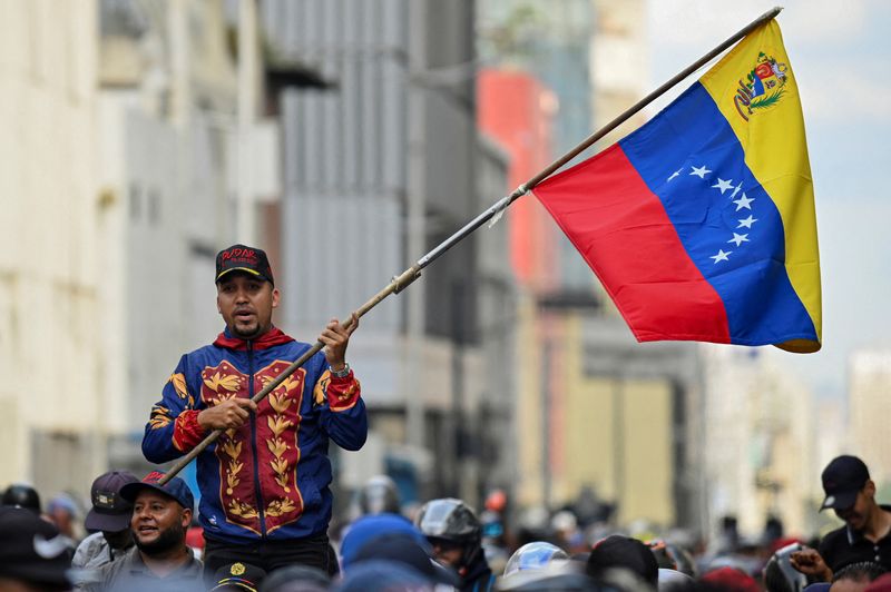 A demonstrator holds a Venezuelan flag during a march outside the National Assembly, on the day Vice President Delcy Rodriguez was formally sworn in as Venezuela's interim president, as U.S.-deposed President Nicolas Maduro appeared in a New York court after the Trump administration removed him from power, in Caracas, Venezuela January 5, 2026. REUTERS/Maxwell Briceno