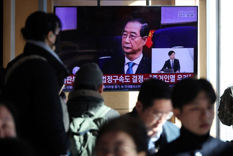 People watch a TV broadcasting a news report on South Korea's Seoul Central District Court ruling on charges against former Prime Minister Han Duck-soo for engaging in a key action of insurrection concerning ex-President Yoon Suk Yeol's declaration of martial law in December 2024, in Seoul, South Korea, January 21, 2026.    REUTERS/Kim Hong-Ji