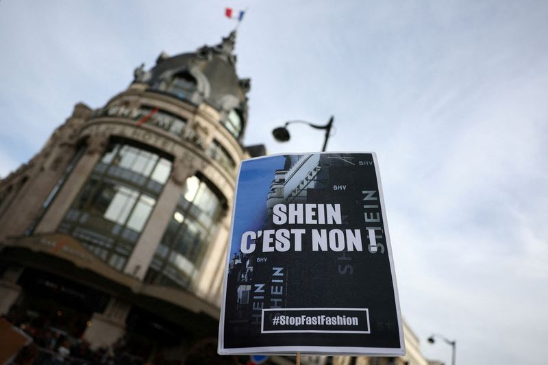 FILE PHOTO: A protester holds a placard which reads "Shein, no way. Stop fast fashion" during a protest against the opening of the first physical space of Chinese online fast-fashion retailer Shein at the Le BHV Marais department store, the Bazar de l'Hotel de Ville, in Paris, France, November 5, 2025. REUTERS/Abdul Saboor/File Photo