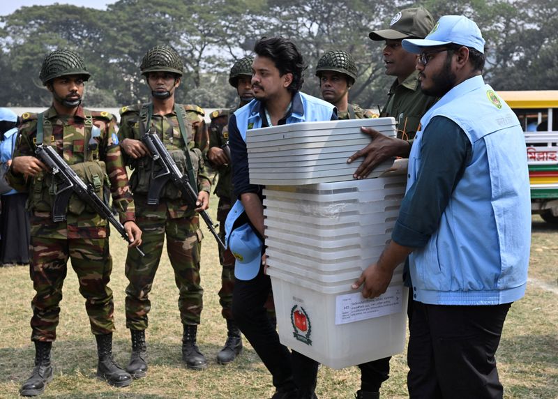 Ansar and VDP members carry ballot boxes out of a distribution center to move them to a voting centre, a day ahead of the national election in Dhaka, Bangladesh, February 11, 2026. REUTERS/Fatima Tuj Johora