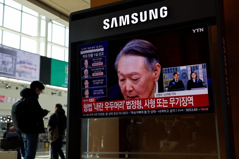 A person stands near a TV screen broadcasting a news report on the sentencing trial of South Korean former president Yoon Suk Yeol's insurrection case, stemming from his short-lived declaration of martial law in December 2024, in Seoul, South Korea, February 19, 2026. REUTERS/Kim Soo-hyeon