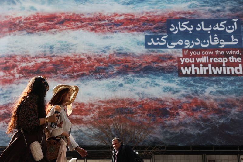 Iranian women walk past an anti-U.S. billboard in Tehran, Iran, February 19, 2026. Majid Asgaripour/WANA (West Asia News Agency) via REUTERS