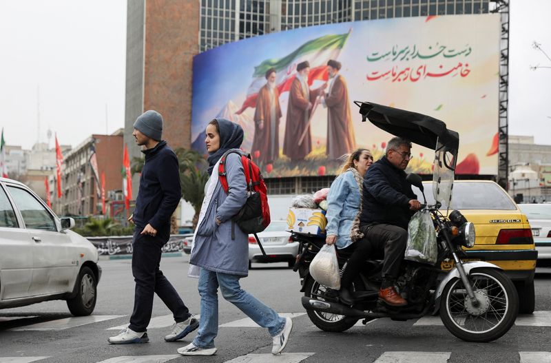 People walk on a street with a banner of Iran's new supreme leader Mojtaba Khamenei with late supreme leader Ayatollah Ali Khamenei and late supreme leader Ayatollah Ruhollah Khomeini in the background, amid the U.S.-Israeli conflict with Iran, in Tehran, Iran, March 10, 2026. Majid Asgaripour/WANA (West Asia News Agency) via REUTERS