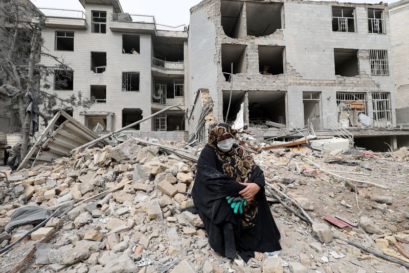 A woman sits outside her destroyed apartment after it was damaged by an airstrike while she was inside, amid the U.S.-Israeli conflict with Iran, in Tehran, Iran, March 12, 2026. REUTERS/Alaa Al Marjani