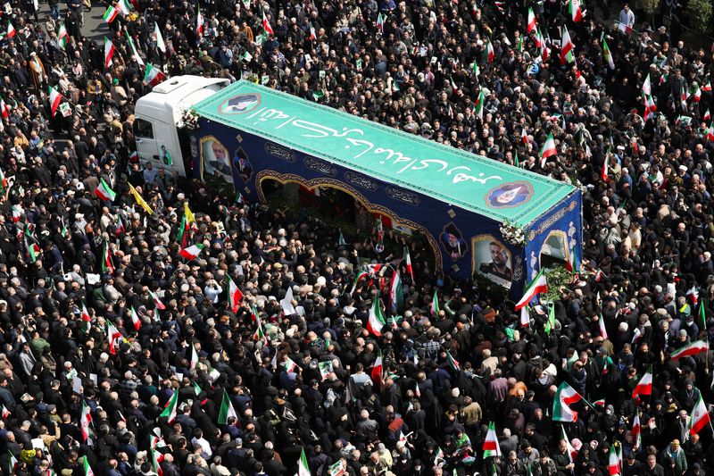 People gather around the coffin of Iranian security chief Ali Larijani during a funeral for Larijani and victims of the IRIS Dena warship at Enghelab Square, amid the U.S.-Israeli conflict with Iran, in Tehran, Iran, March 18, 2026. REUTERS/Alaa Al Marjani