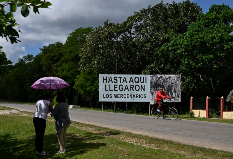 Two women connect to the internet near a billboard reading "The mercenaries reached this far" as Cuba marks the 65th anniversary of its victory over the CIA-backed Bay of Pigs invasion, amid a U.S. oil blockade and threats from U.S. President Donald Trump, in Palpite, Cienaga de Zapata, Cuba April 7, 2026. REUTERS/Norlys Perez