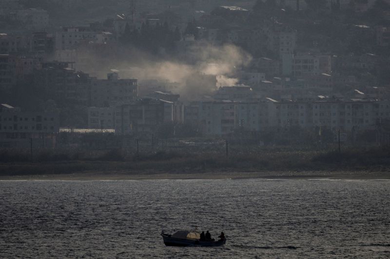 FILE PHOTO: Fishermen sail their boat as smoke from an Israeli airstrike rises in Abbassiye area in Tyre, Lebanon, April 14, 2026. REUTERS/Louisa Gouliamaki/File Photo