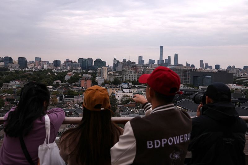 People look at the city skyline at a rooftop of a building in Beijing, China October 18, 2025. REUTERS/Tingshu Wang