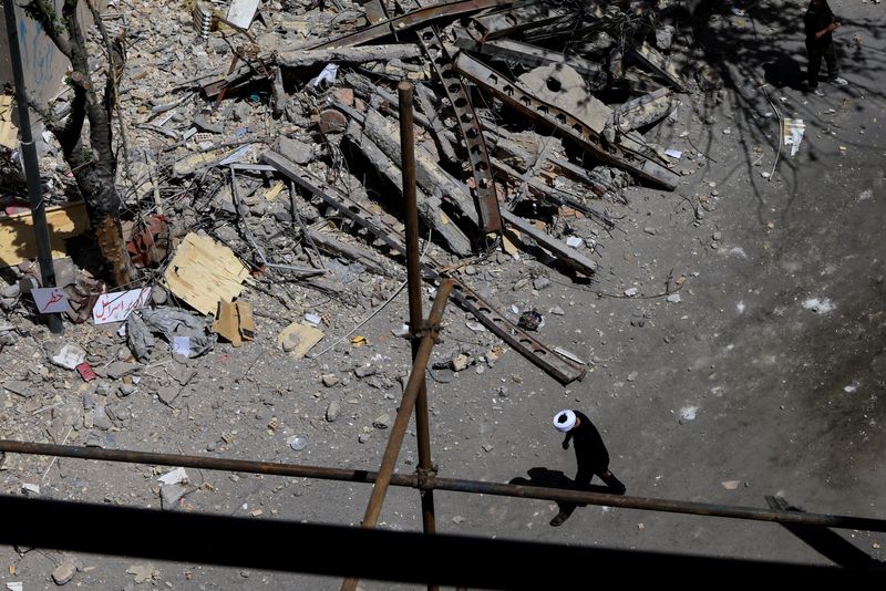 A cleric walks near a residential building damaged by a strike on March 4, in Tehran, Iran, April 14, 2026. REUTERS/Thaier Al Sudani