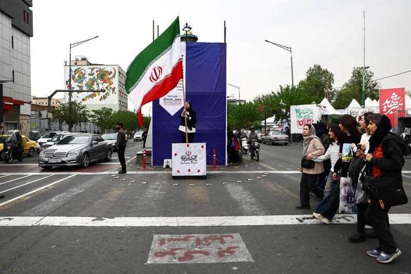 A woman holds an Iranian flag on a street, amid a ceasefire between U.S. and Iran, in Tehran, Iran, April 20, 2026. Majid Asgaripour/WANA (West Asia News Agency) via REUTERS