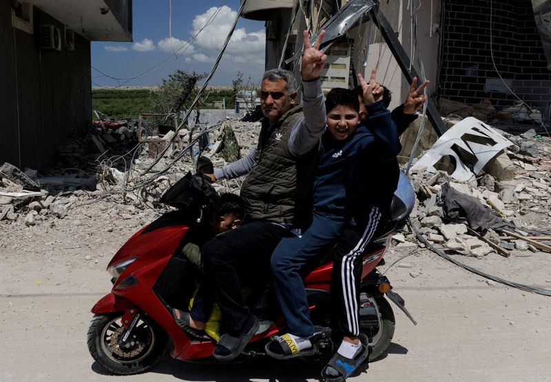 People flash a victory sign as they ride a motorcycle damaged by an Israeli strike, amid a 10-day ceasefire between Lebanon and Israel, in Mansouri village, southern Lebanon, April 21, 2026. REUTERS/Zohra Bensemra