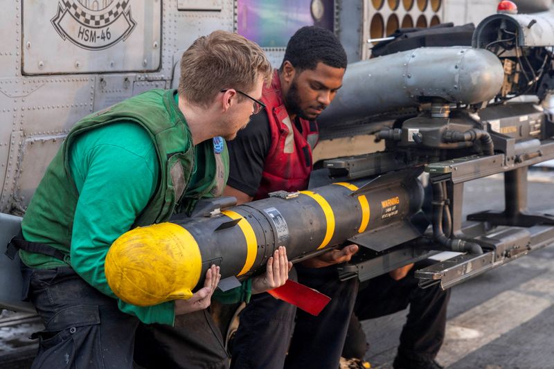 U.S. sailors, assigned to Helicopter Maritime Strike Squadron 46, unload an AGM-114 Hellfire missile from an MH-60R Sea Hawk helicopter on the flight deck of Arleigh Burke-class guided-missile destroyer USS Delbert D. Black supporting Operation Epic Fury during the Iran war at an undisclosed location, March 23, 2026. U.S. Navy/Handout via REUTERS