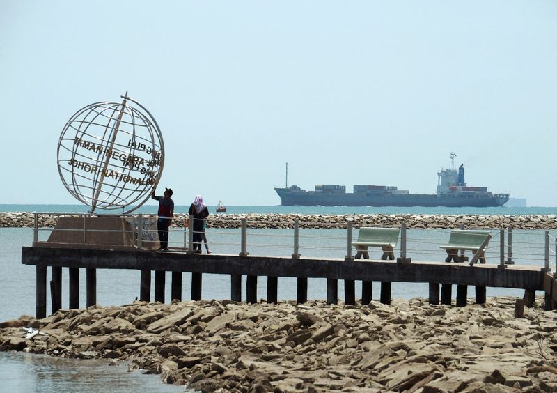 FILE PHOTO: A container ship enters the Singapore Strait for the Strait of Malacca, as tourists stand at mainland Asia's southern most point in Johor, Malaysia November 12, 2016. Picture taken November 12, 2016.  REUTERS/Henning Gloystein/File Photo