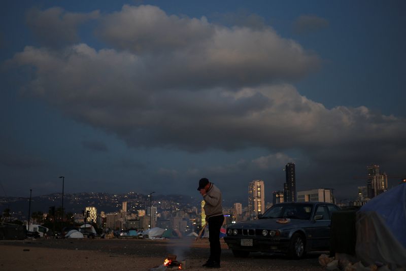 FILE PHOTO: A displaced man lights a fire outside his tent at a makeshift encampment, amid a 10-day ceasefire between Lebanon and Israel, in Beirut, Lebanon, April 21, 2026. REUTERS/Saleh Salem/File Photo