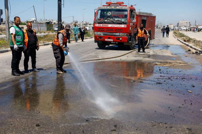 Members of civil defence personnel use a fire hose at the site of an Israeli airstrike on a car in the central Gaza Strip, April 23, 2026. REUTERS/Mahmoud Issa