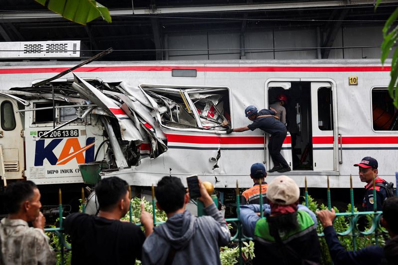 People watch as a technician works at the site after a deadly collision between a commuter line train and a long-distance train, in Bekasi, on the outskirts of Jakarta, Indonesia, April 28, 2026. REUTERS/Willy Kurniawan