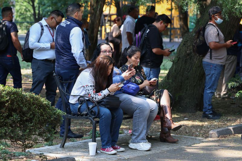 People sit on a bench while they wait outside, after an earthquake alarm sounded warning of a tremor, in Mexico City, Mexico, May 4, 2026. REUTERS/Luis Cortes