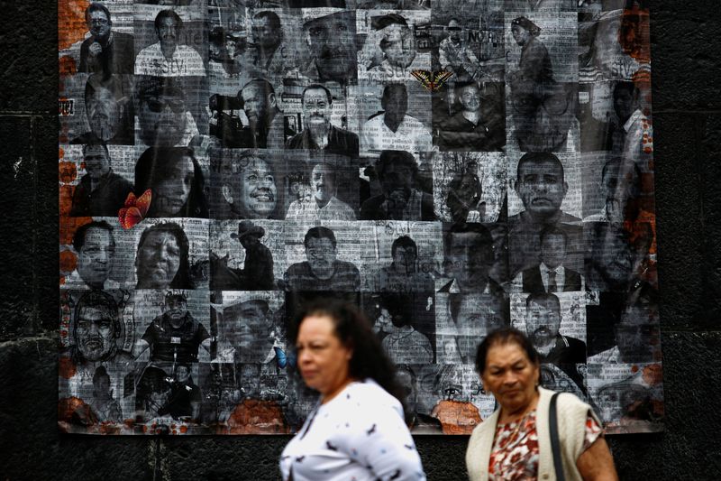 People walk by pictures of murdered journalists and activists displayed on an altar on the eve of the Day of the Dead in Mexico City, Mexico, October 31, 2022. REUTERS/Gustavo Graf/File Photo