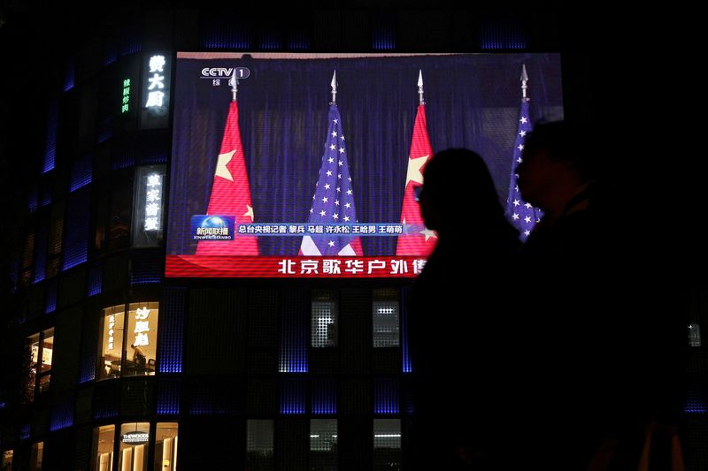 FILE PHOTO: A large screen shows news footage of Chinese and U.S. flags during the bilateral meeting between Chinese President Xi Jinping and U.S. President Donald Trump on the sidelines of the Asia-Pacific Economic Cooperation (APEC) summit in South Korea's Busan, outside a shopping mall in Beijing, China October 30, 2025. REUTERS/Florence Lo/File Photo