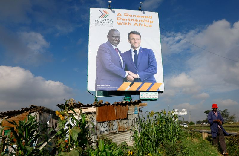 A pedestrian walks near a billboard featuring Kenyan President William Ruto and French President Emmanuel Macron ahead of the "Africa Forward" Summit, in the outskirts of Nairobi, Kenya May 7, 2026. REUTERS/Thomas Mukoya