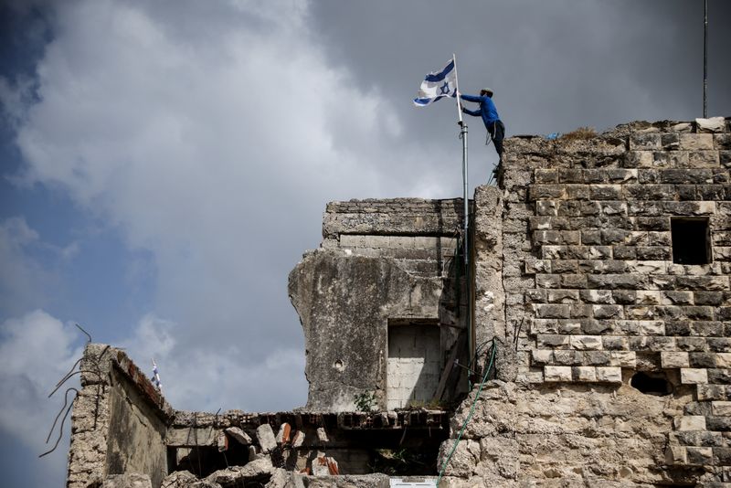 An Israeli settler places an Israeli flag, on the day of the re-establishment of the settlement of Sa-Nur, which was evacuated as part of Israel’s 2005 disengagement, in Sa-Nur in the Israeli-occupied West Bank, April 19, 2026. REUTERS/Shir Torem