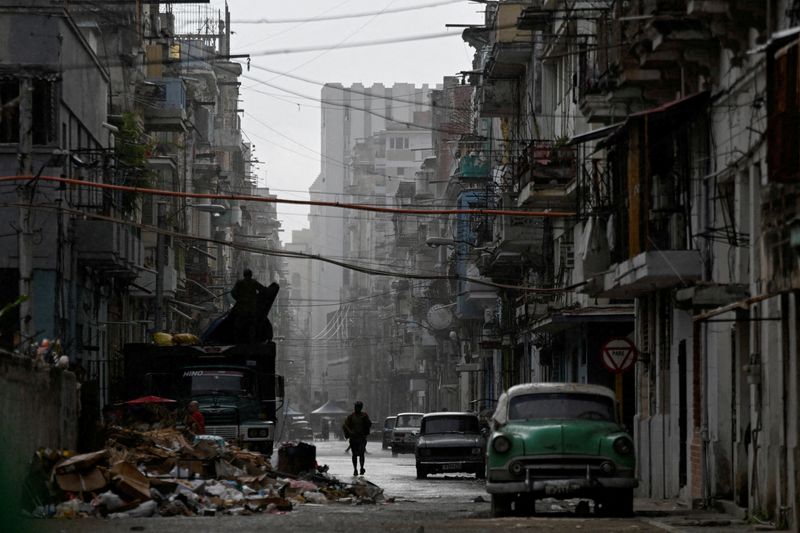 FILE PHOTO: A man walks on a street in the rain as Cuba reconnected its electrical grid across much of the island, according to the Energy and Mines Ministry, following a nationwide blackout that left about 10 million people without electricity, in Havana, Cuba, March 17, 2026. REUTERS/Norlys Perez/File Photo