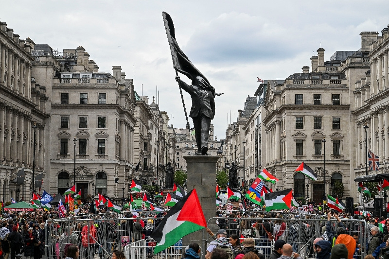 People hold Palestinian flags next to a statue, depicting a figure carrying a flag covering their face and stepping off a plinth, by British street artist Banksy during a march, held by Palestine Solidarity Campaign, to mark the 78th anniversary of the Nakba and against the "Unite the Kingdom" rally taking place in London organised by British anti-immigration activist Stephen Yaxley-Lennon, also known as Tommy Robinson, in London, Britain, May 16, 2026. REUTERS/Chris J Ratcliffe