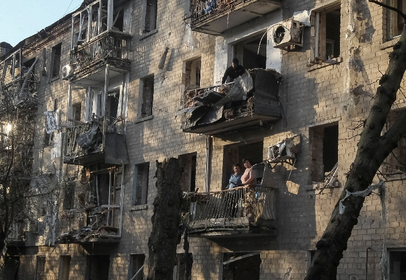FILE PHOTO: Residents stand at a balcony of an apartment building damaged during  a Russian missile strike, amid Russia's attack on Ukraine, in Dnipro, Ukraine May 18, 2026. REUTERS/Stringer/File Photo