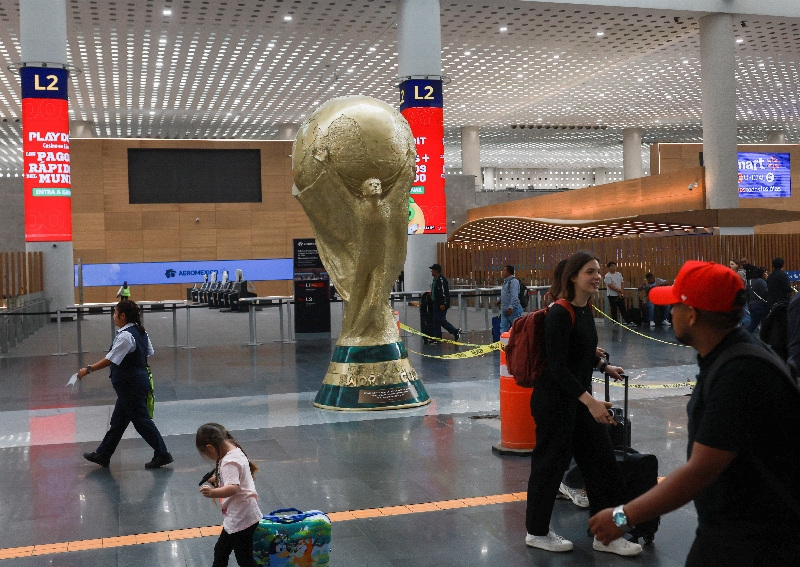 Passengers walk past a giant replica of the World Cup trophy displayed at Mexico City International Airport ahead of the World Cup's opening match on June 11, in Mexico City, Mexico, May 18, 2026. REUTERS/Henry Romero