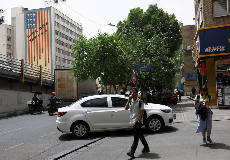 People walk near an anti-U.S. mural on a building in Tehran, Iran, May 19, 2026. Majid Asgaripour/WANA (West Asia News Agency) via REUTERS