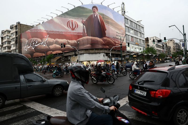 People ride motorcycles near a billboard featuring an image of Iran's new Supreme Leader Mojtaba Khamenei, amid a ceasefire between U.S. and Iran, in Tehran, Iran, April 20, 2026. Majid Asgaripour/WANA (West Asia News Agency) via REUTERS