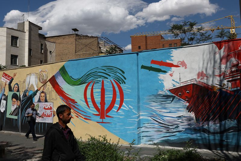 People walk on a street near a mural featuring an image of the late Supreme Leader of Iran, Ayatollah Ali Khamenei, in Tehran, Iran, May 18, 2026. Majid Asgaripour/WANA (West Asia News Agency) via REUTERS