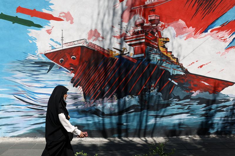 A woman walks next to a mural on a street in Tehran, Iran, May 18, 2026. Majid Asgaripour/WANA (West Asia News Agency) via REUTERS