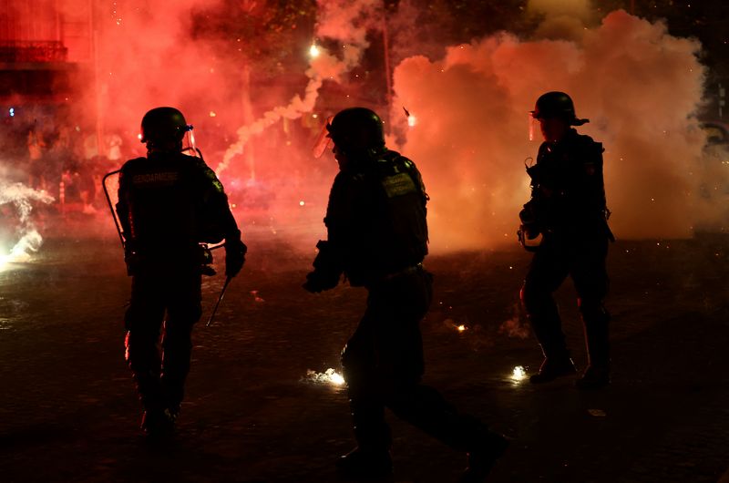 Soccer Football - UEFA Champions League -  Paris St Germain fans celebrate winning the UEFA Champions League - Paris, France - May 31, 2026 Police officers protect themselves from flares after Paris St Germain won the UEFA Champions League REUTERS/Abdul Saboor