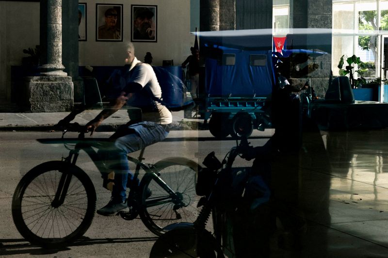 FILE PHOTO: People are reflected in a window of the Central Palace of Computing and Electronics bearing images of late Cuban President Fidel Castro and his brother, former President Raul Castro, who was indicted in the United States in a move that marks an escalation in Washington's pressure campaign against the Caribbean island's communist government, in Havana, Cuba May 20, 2026. REUTERS/Norlys Perez/File Photo