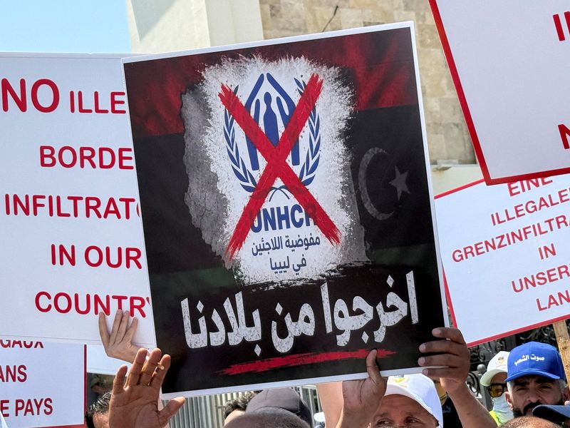 Protesters hold signs as they gather outside the headquarters of the United Nations High Commissioner for Refugees (UNHCR), demanding that the organisation leave the country and calling for an end to migrant settlement and the deportation of migrants and refugees, in Tripoli, Libya, June 4, 2026. Picture taken with a mobile phone. REUTERS/Ayman al-Sahili