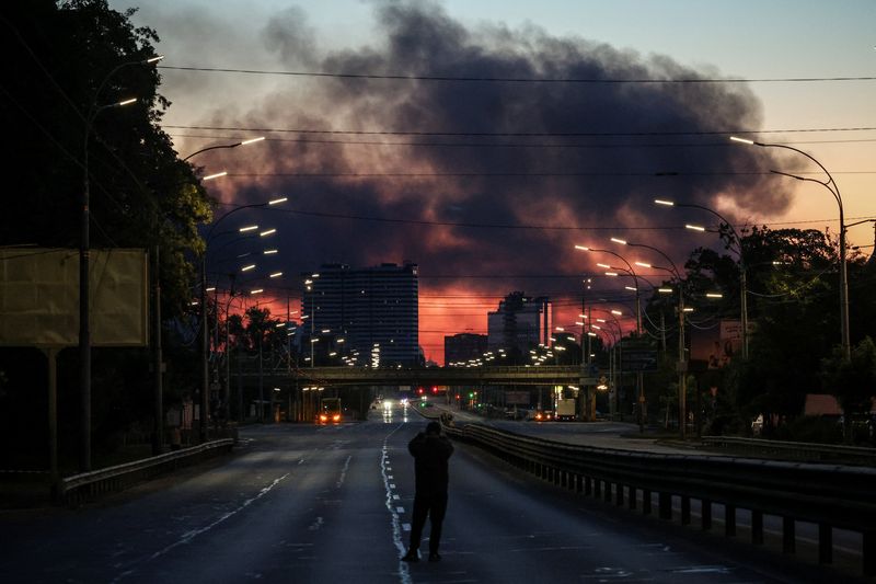 A man takes a picture of a street as smoke rises in the background after an overnight Russian missile and drone strike, amid Russia's attack on Ukraine, in Kyiv, Ukraine June 2, 2026. REUTERS/Alina Smutko