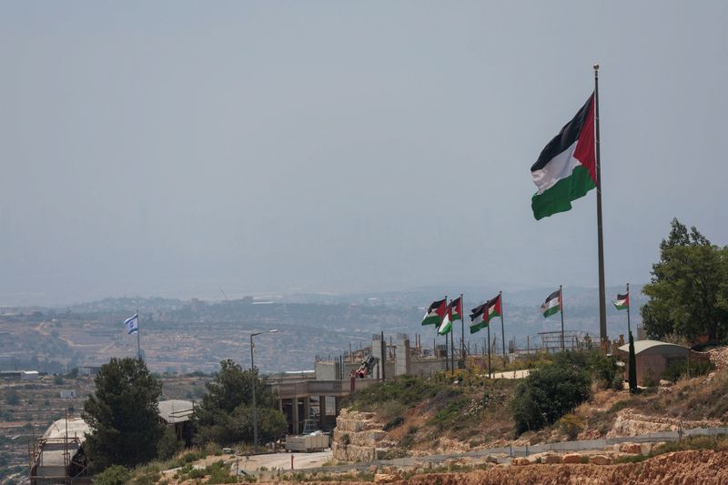 An Israeli flag flutters at a new Israeli settlement, behind Palestinians flags near Ramallah, in the Israeli-occupied West Bank, Jun 1, 2026. REUTERS/Mohammed Torokman