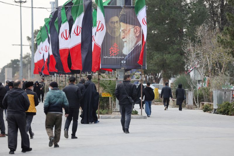 FILE PHOTO: People walk along a street with Iranian flags and a poster with images of Iran's late Supreme Leader Ayatollah Ali Khamenei, amid the U.S.-Israeli conflict with Iran, in Tehran, Iran, March 9, 2026. Majid Asgaripour/WANA (West Asia News Agency) via REUTERS/File Photo