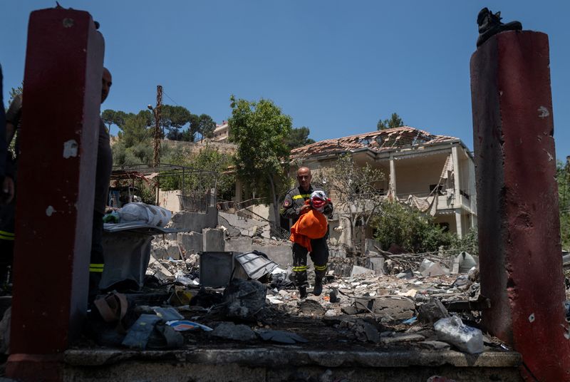 A member of the government-run Lebanese Civil Defense, the country's primary firefighting, first aid, and rescue force, holds a national flag and personal belongings salvaged from the rubble while inspecting their headquarters in Nabatieh, Lebanon, June 17, 2026, following the deal between the United States and Iran. The headquarters was destroyed in an Israeli airstrike in May. REUTERS/Zohra Bensemra