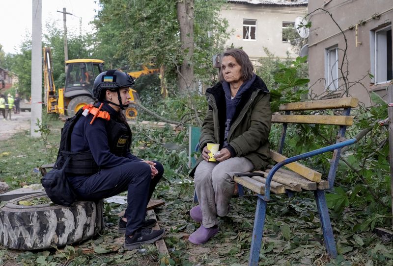An emergency psychologist talks to a resident at the site of an apartment building hit by a Russian air strike, amid Russia's attack on Ukraine, in Kharkiv, Ukraine June 20, 2026. REUTERS/Sofiia Gatilova