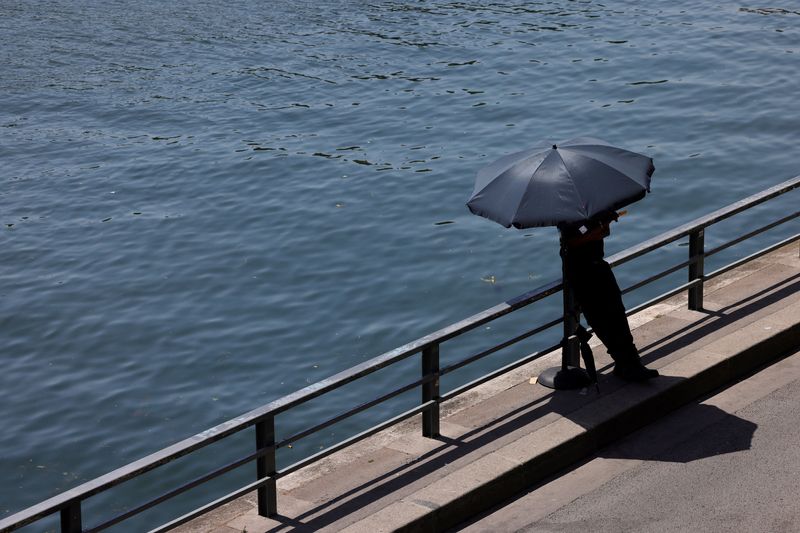 A person shelters from the sun under an umbrella along the banks of the River Seine in Paris as temperatures rise during a heatwave affecting a large part of France, June 22, 2026. REUTERS/Alice Sacco