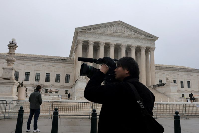 A person uses a video camera to record outside the U.S. Supreme Court building in Washington, D.C., U.S., February 20, 2026. REUTERS/Jonathan Ernst