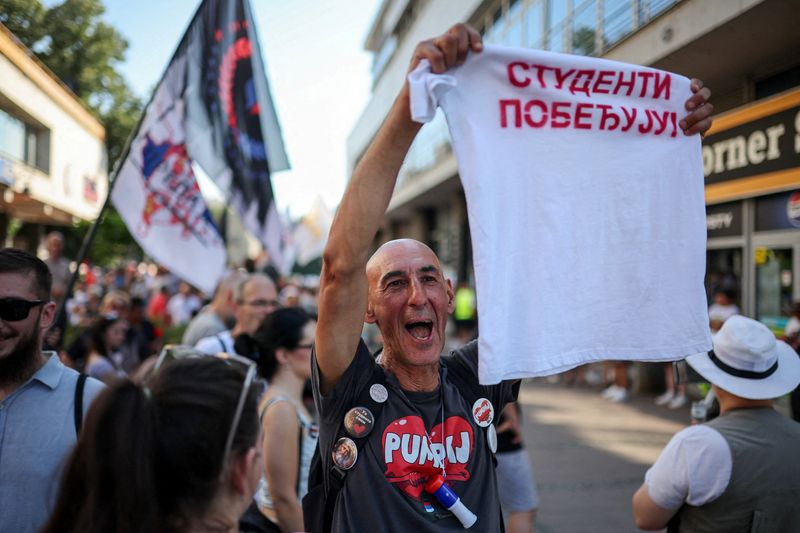 A man holds a t-shirt that reads "Students are winning" as people gather for a protest, as part of a nationwide anti-government movement triggered by the deadly collapse of the Novi Sad railway station canopy in November 2024, following Serbian President Aleksandar Vucic's resignation announcement, in Kraljevo, Serbia, June 28, 2026. REUTERS/Djordje Kojadinovic
