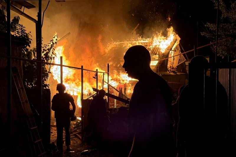 Residents look at a private house that burns after an overnight Russian drone strike, amid Russia's attack on Ukraine, in Zaporizhzhia, Ukraine June 22, 2026. Picture taken with a mobile phone. REUTERS/Serhii Chalyi