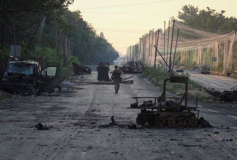 A serviceman of the consolidated Brigade 'Khyzhak' of the Ukrainian Patrol Police Department walks along a road near anti-drone nets and destroyed military vehicles as he takes part in a mission to protect a road from Russian drones between frontline towns of Druzhkivka and Kostiantynivka, amid Russia's attack on Ukraine, in Donetsk region, Ukraine June 24, 2026. REUTERS/Anatolii Stepanov