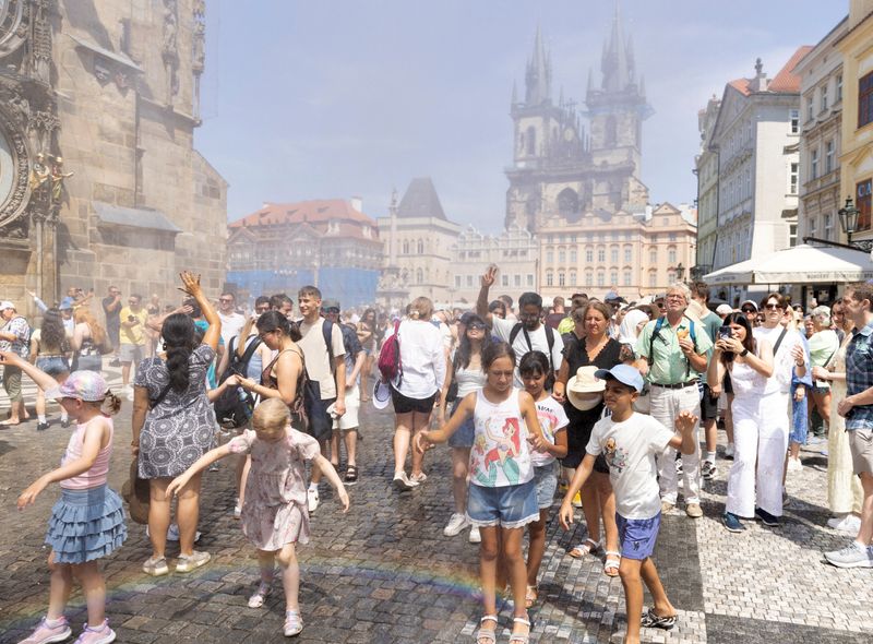 People are sprayed with water to cool down during a hot, sunny day, as the country records temperatures above 40 degrees Celsius, according to the Czech Hydrometeorological Institute, at Old Town Square in Prague, Czech Republic, June 28, 2026. REUTERS/Eva Korinkova