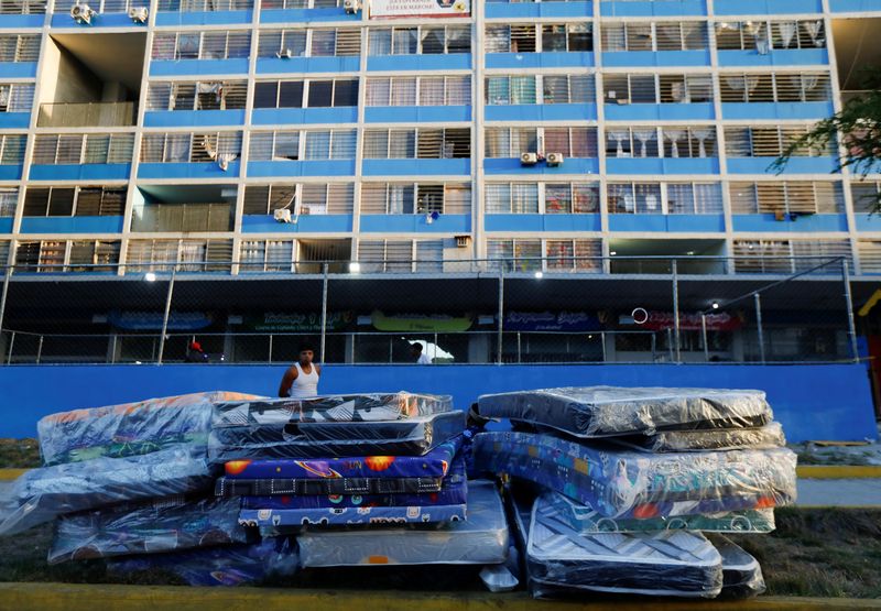 A person watches over mattresses outside a building that was deemed too damaged and whose residents were evacuated after deadly earthquakes struck the country, in Caracas, Venezuela, June 27, 2026. REUTERS/Fausto Torrealba
