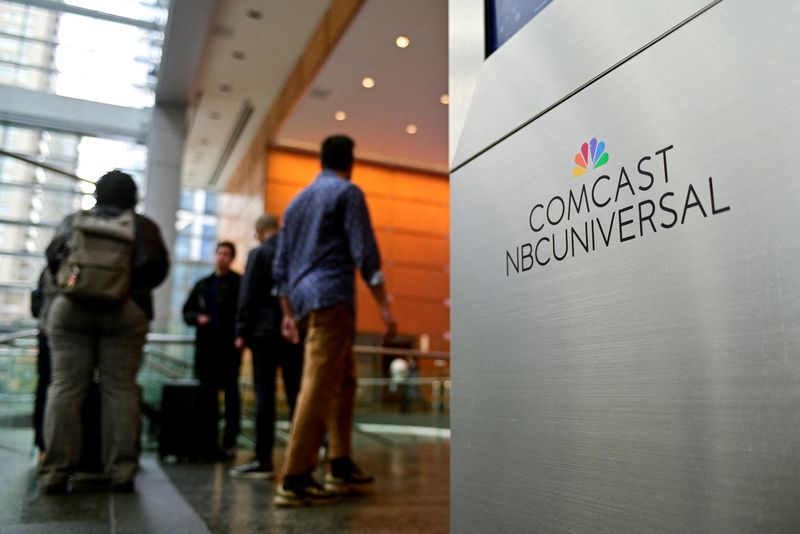 FILE PHOTO: People stand near a signage of Comcast and NBC Universal in the lobby of the corporate headquarters of Comcast, in Philadelphia, Pennsylvania, U.S. November 20, 2024. REUTERS/Bastiaan Slabbers/File Photo