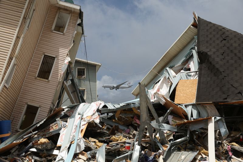 Debris lies on the street amid damaged buildings with an aircraft flying in the background, in the aftermath of the June 24 earthquakes, in La Guaira, Venezuela, July 6, 2026. REUTERS/Ricardo Arduengo